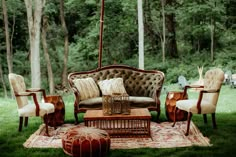 an old fashioned couch sitting on top of a rug in the middle of a field