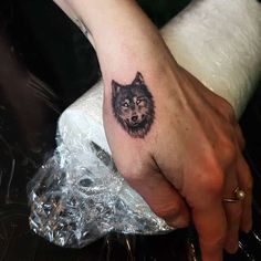 a woman's hand with a wolf tattoo on it