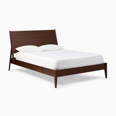 a bed with white sheets and wooden headboard