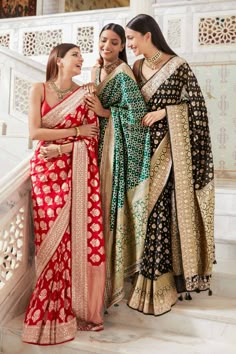 three women in sari standing next to each other on the stairs at a palace