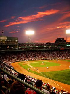 a baseball game is being played in a stadium at night with the sun going down