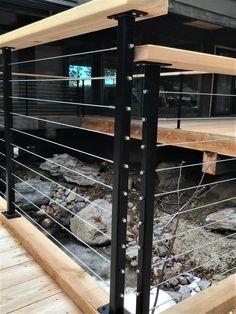 a wooden deck with metal railings and rocks on the ground in front of a building