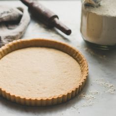 an uncooked pie crust sits on a counter next to some baking utensils