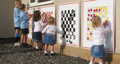 several children standing in front of a wall with pictures on it