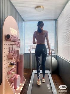 a woman is standing on a treadmill and looking out the window with her back to the camera