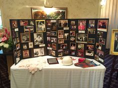 a table topped with pictures and photos next to a wall full of framed photographs on it