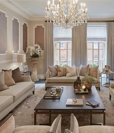 a living room filled with furniture and a chandelier hanging from the ceiling over a fire place