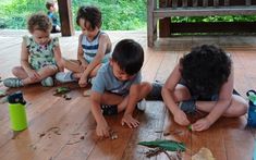 four children sitting on the floor playing with leaves