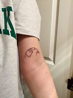 a person with a tattoo on their arm that has the earth in it's center