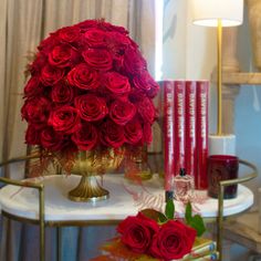 a table topped with a vase filled with red roses next to candles and other items