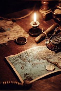 an old world map, compass, money and candle on a table with other items