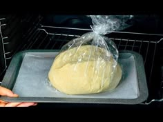 a loaf of bread sitting on top of a pan in an oven with plastic wrap