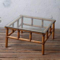 a glass and bamboo coffee table sitting on top of a wooden floor