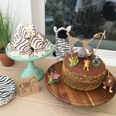 there is a cake on the table with zebras and giraffe figurines