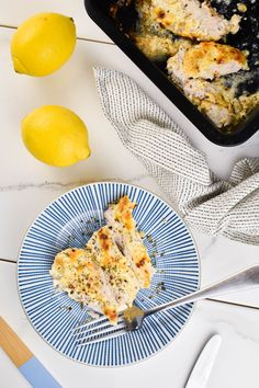 a slice of chicken casserole on a blue plate next to two lemons