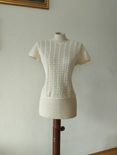 A rare 1970s white crochet shirt in beautifully designed crochet pattern. At the back of the neckline the shirt closes with a button. The crochet is 100% cotton. MEASUREMENTS (taken flat)* Armpit-to-armpit: 18'' (46 cm) Width: 15'' (38 cm) Length: 20'' (50 cm) Condition is excellent. There are no visible flaws. *Please compare measurements to a garment you currently own to ensure proper fit. visit the shop: http://www.etsy.com/shop/sherpavintage instagram | sherpa_vintage Fitted Cream Crochet Top With Pointelle Knit, Fitted Crochet Top With Pointelle Knit And Short Sleeves, Cotton Crochet Lace Top With Short Sleeves, Vintage Cream Crochet Top, Vintage White Crochet Lace Top, Vintage White Tops With Crochet Lace, Fitted White Pointelle Knit Blouse, Fitted Cotton Crochet Top With Pointelle Knit, Vintage White Top With Crochet Lace