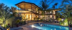 an outdoor swimming pool surrounded by greenery and trees at night with the lights on