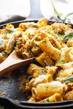 a skillet filled with pasta and meat on top of a wooden spoon in it