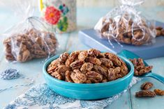 a blue bowl filled with nuts on top of a table next to two bags of walnuts