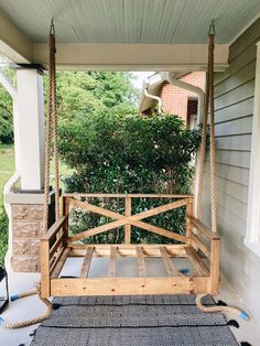 a porch swing that has been made into a bed frame and is attached to the side of a house