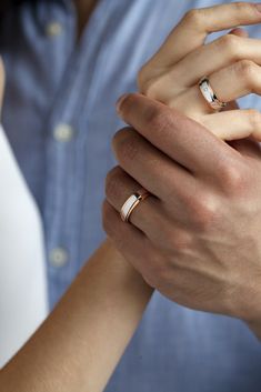 two people holding hands with wedding rings on their fingers, both wearing gold and silver bands