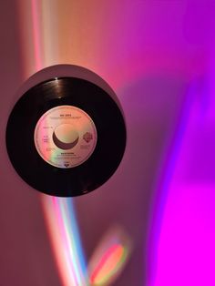 an old record is being held up in front of a colorful background with light coming from the disc