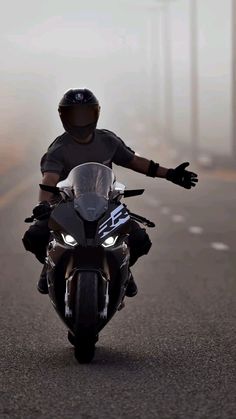 a person riding on the back of a motorcycle down a foggy road with their arms outstretched