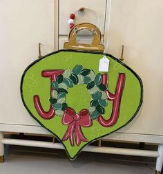 a green sign with the word joy hanging from it's side in front of a white cabinet