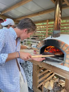 a man is cooking food in an outdoor oven with wood and fire on the grill