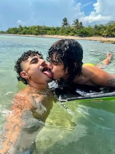 two people are in the water with their mouths open and one person is laying on a surfboard