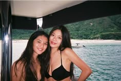 two women in bikinis on a boat posing for the camera with their arms around each other