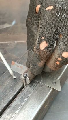 a pair of gloves that are on top of a piece of metal with holes in it