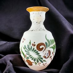 a white vase sitting on top of a black cloth