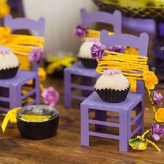 cupcakes are sitting on purple chairs with yellow ribbons and flowers around the edges