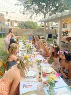 a group of women sitting at a table with plates and flowers in their hair,