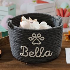 a black basket with white lettering and a cat on the inside that says,'bella '