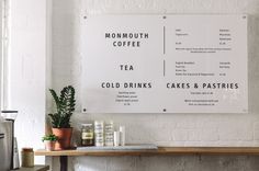 there is a menu on the wall next to some cups and coffee mugs in front of it