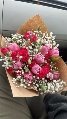 a bouquet of pink and red flowers in someone's lap while they are driving