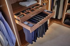 an open drawer in a closet filled with clothes