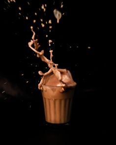 chocolate milk splashing into a glass on a black background, with the light coming from behind it