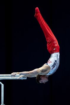 a man is doing a handstand on the bars in an artistic gymnastics competition