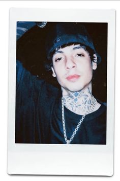 a young man with tattoos wearing a baseball cap and chain around his neck is looking at the camera