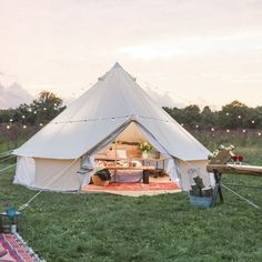 a white tent sitting on top of a lush green field next to a picnic table