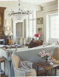 a living room filled with lots of furniture and a chandelier hanging from the ceiling