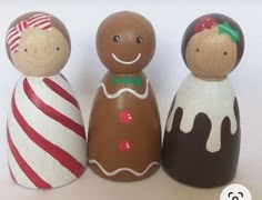 three small wooden dolls are standing next to each other on a white surface with red and green stripes