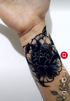 a person's arm with a flower tattoo on it and a hand holding the wrist