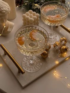 two glasses of champagne on a tray with gold decorations