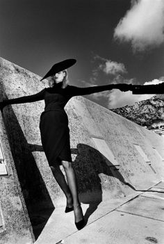 a black and white photo of a woman with her arms outstretched in front of a wall