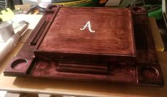 a wooden cutting board with the letter a on it sitting on a table next to other items