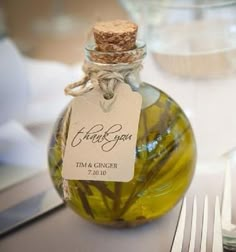 a bottle filled with green liquid sitting on top of a table next to silverware